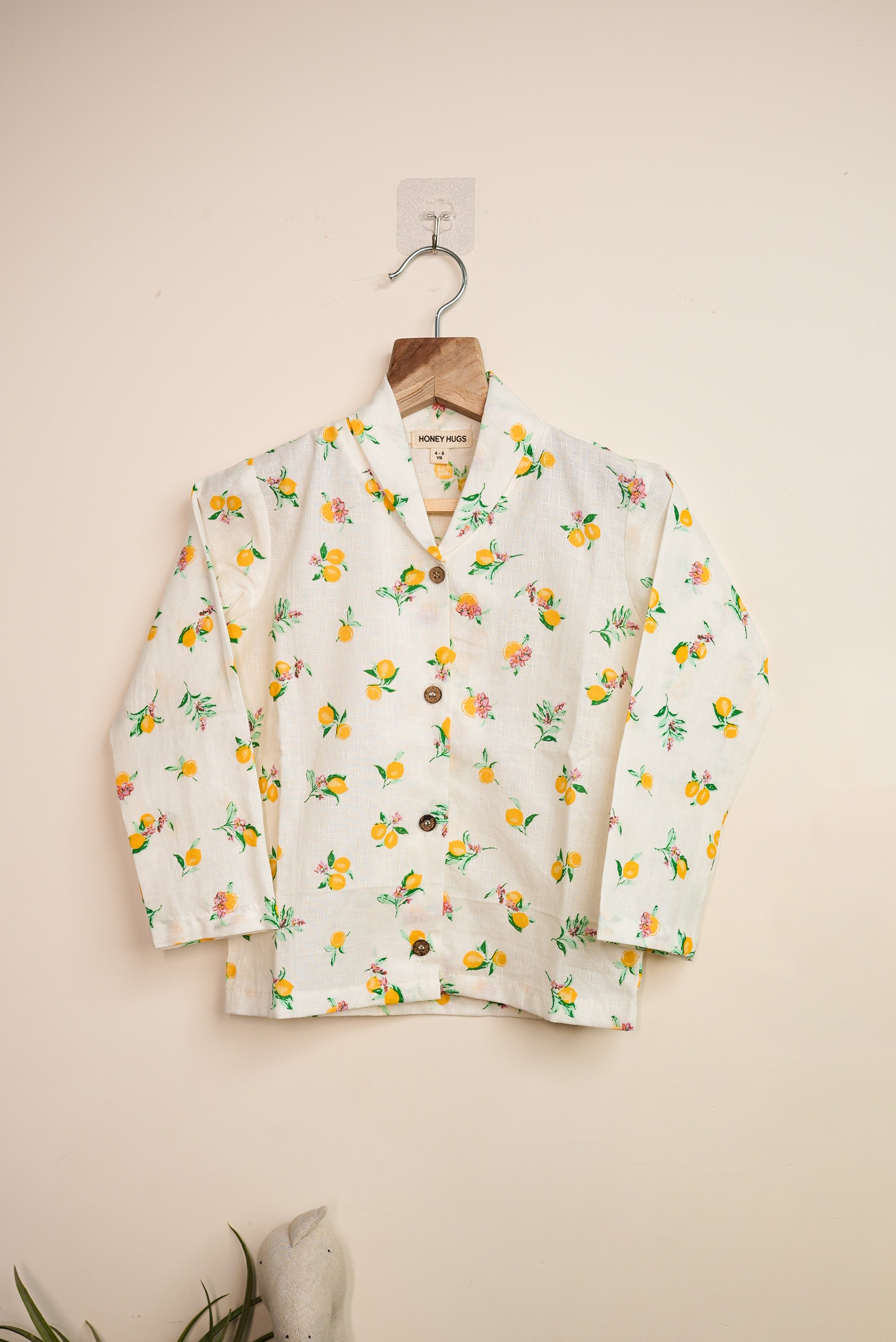 Floral patterned cardigan on a hanger against a beige background