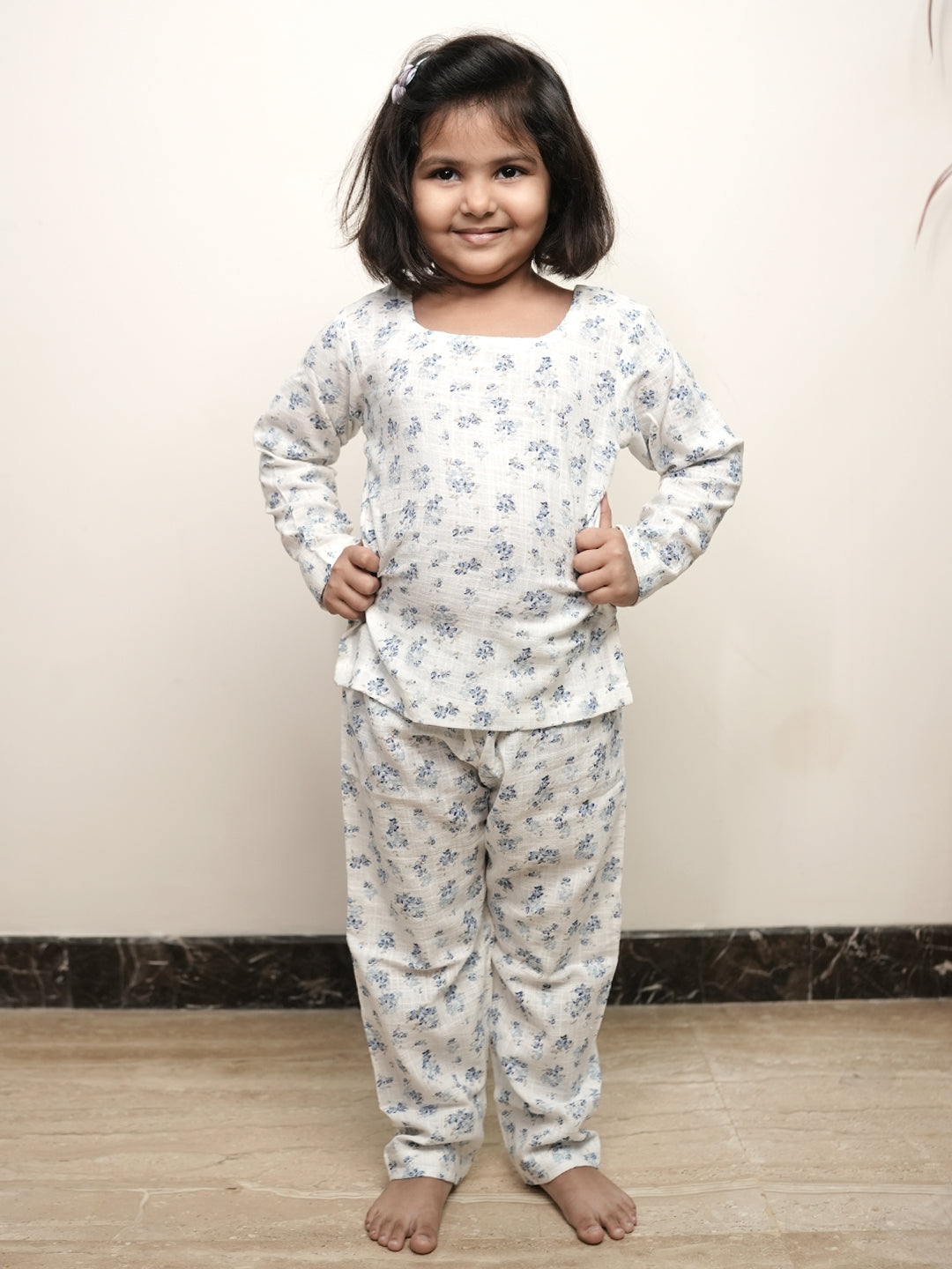 Young girl wearing a floral pajama set against a plain background