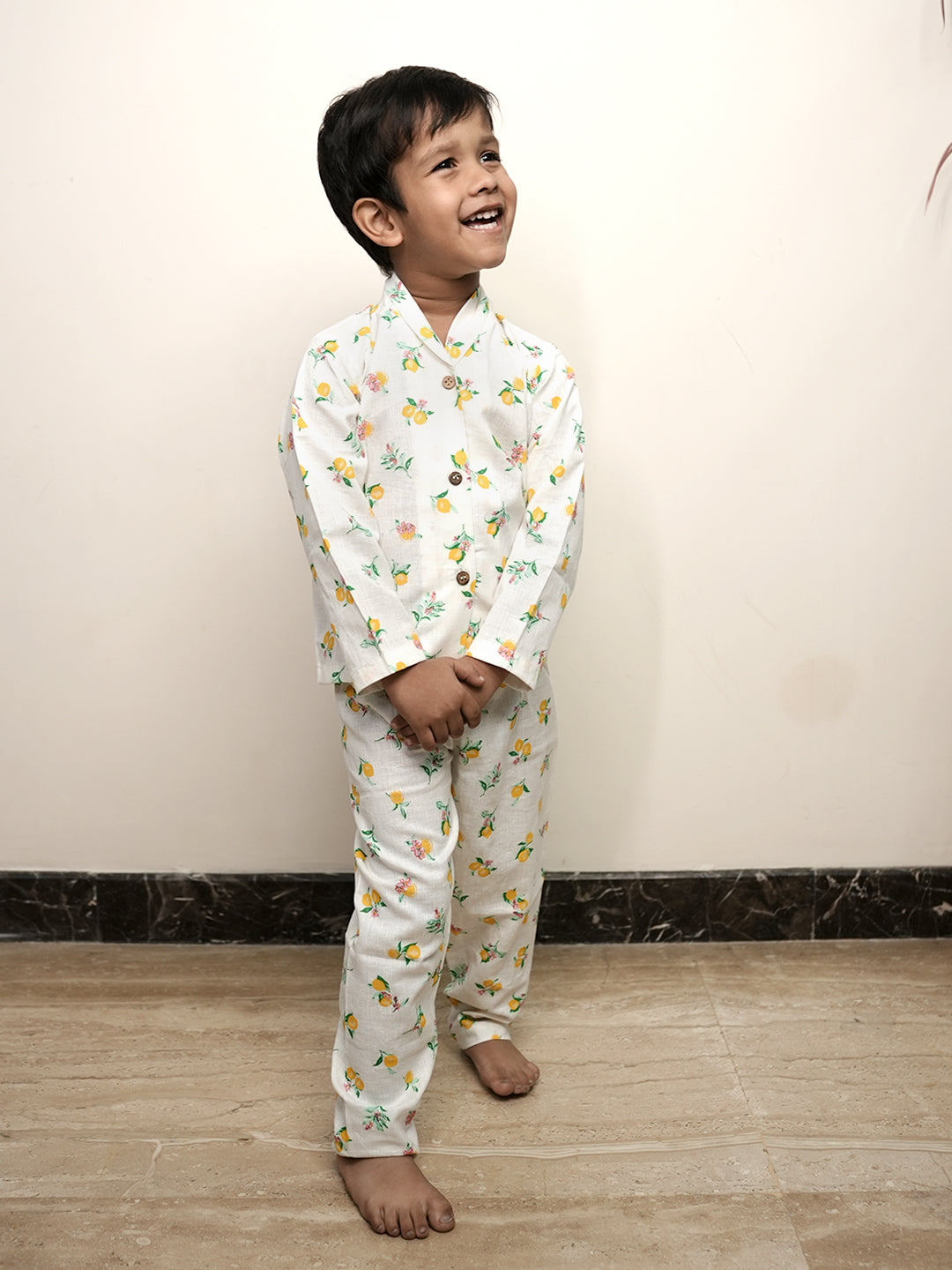 Child wearing a white pajama set with colorful patterns on a plain background