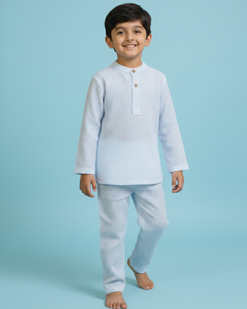 Young boy wearing a light blue pajama set against a light blue background