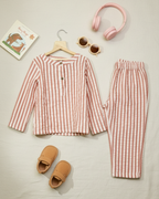 Red and white striped children's outfit with slippers and headphones on a light background