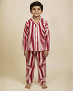 Child wearing red and white striped pajama set on a beige background
