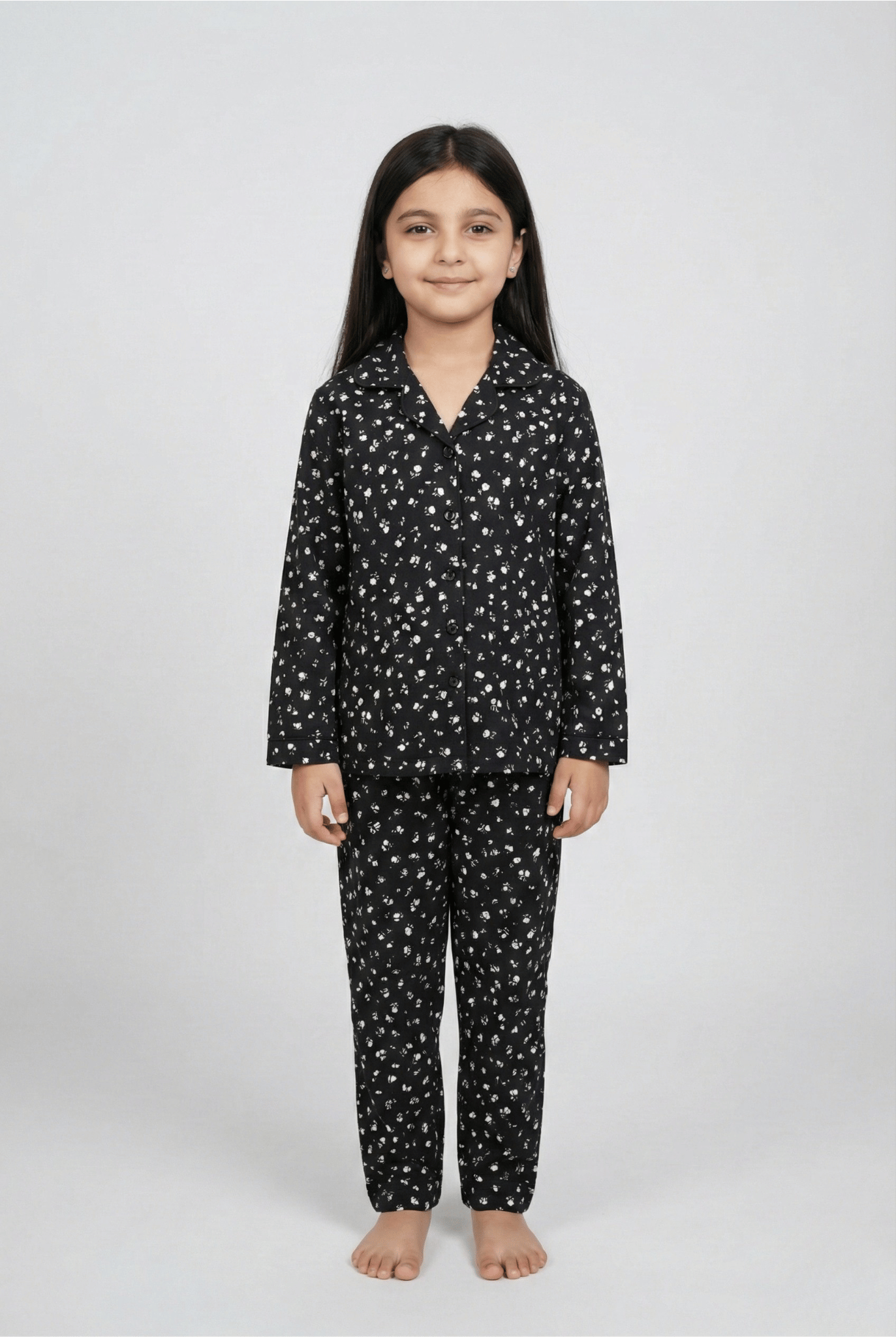 Child wearing a black pajama set with white patterns on a white background