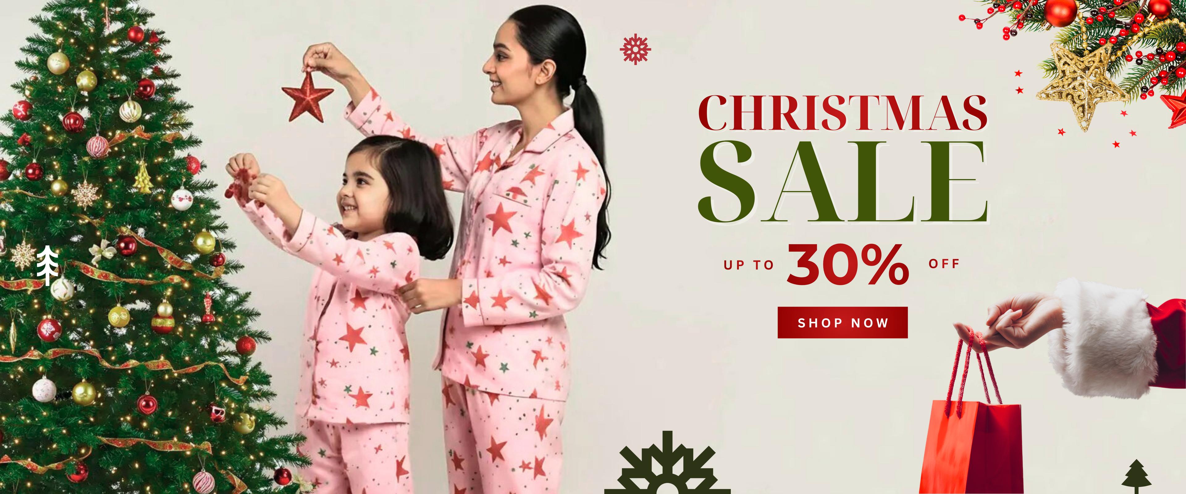 Mother and daughter wearing matching pink Christmas pajamas decorating a Christmas tree during Christmas sale