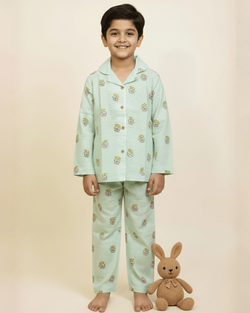 Child wearing a light blue pajama set with animal prints, standing next to a plush toy on a beige background.