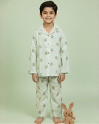 Child wearing a light green pajama set with a bunny design, standing against a light green background.