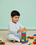 Child playing with colorful building blocks on a light green floor.