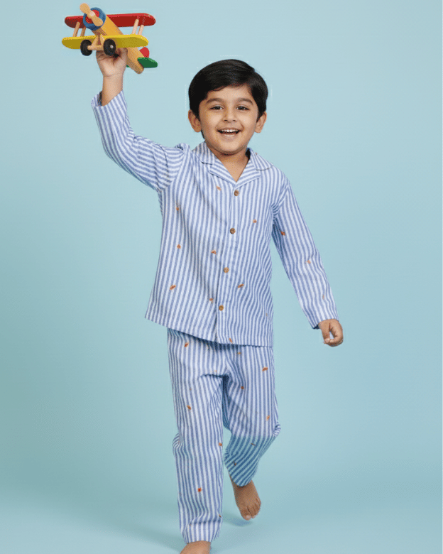 Child wearing striped pajamas holding a toy airplane against a light blue background