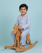 Child sitting on a wooden rocking horse against a light blue background