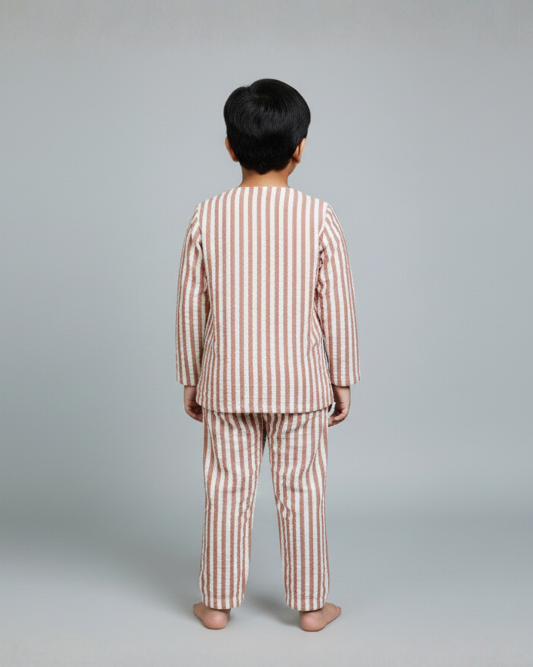 Child wearing a striped pajama set against a plain background